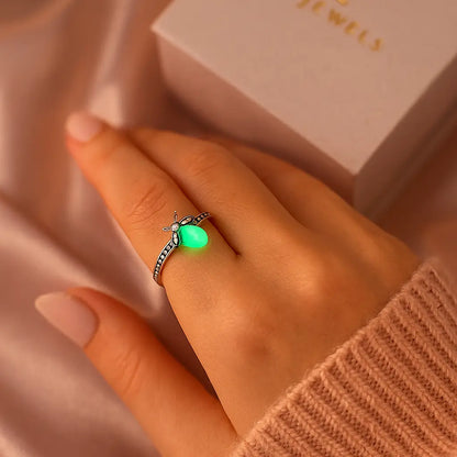 Hand wearing a green glowing ring with a Foie Jewels box in the background