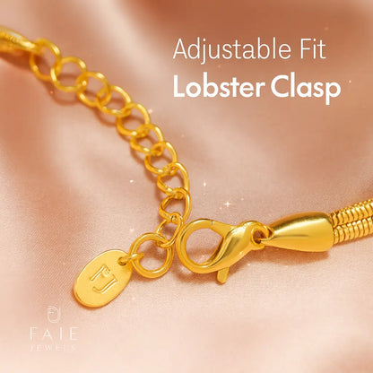 Gold bracelet with lobster clasp on a soft pink background
